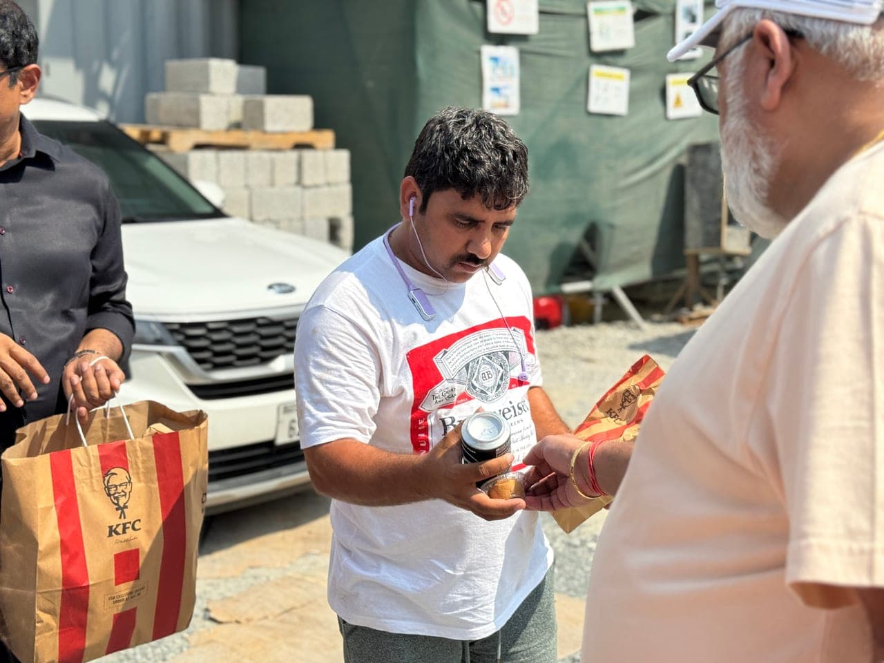 Al Ranim Cares team handing a packed meal to a worker during a Dubai meal distribution drive