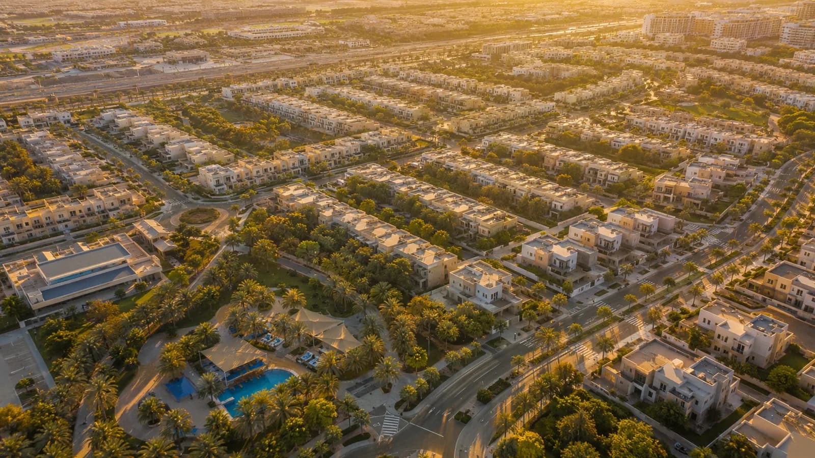 Golden-hour aerial of the Al Furjan villa community with modern villas, greenery and pools