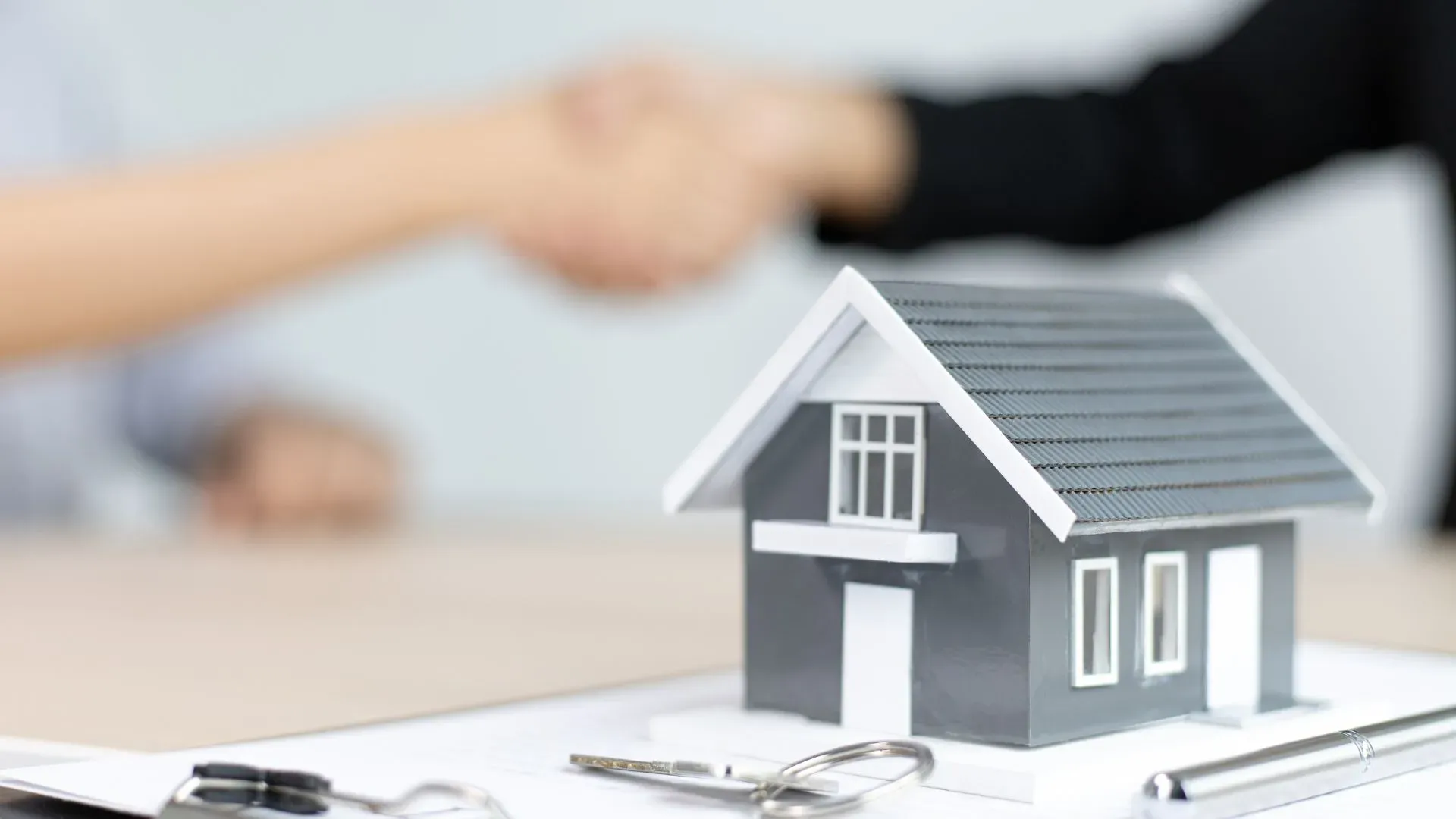 Real estate agent handshake with house model and keys symbolising successful property purchase in Dubai using cryptocurrency